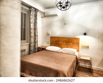 A modern bedroom with wooden headboard and a chandelier hanging from the ceiling - Powered by Shutterstock
