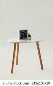Modern bedside table with clock and flowerpot on white background