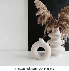 Modern Beige Ceramic Vases With Dry Grass  Branches On White Table Near A Black White Wall Backdrop. Copy Space.Minimal Scandinavian Interior. Neutral Trendy Colors Interior Decoration .