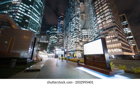 Modern billboard with a green screen on a busy street of the big city in the night. Road traffic and gigantic skyscrapers glittering with neon lights and pedestrians passing by in motion time. - Powered by Shutterstock