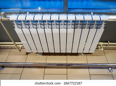 Modern bimetallic heating radiator installed under a window in an industrial building