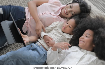 Modern black american family are lie down and spending time together by using tablet computer with happy moment and smiling faces in the house, selective focus.