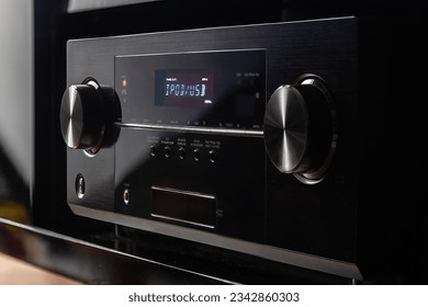 A modern, black audio video receiver with a glossy finish and minimalistic design
