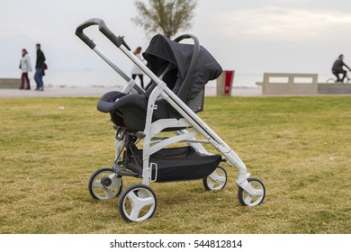 A Modern Black Baby Pram On Grass With Sea Background