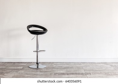 Modern Black Bar Stool In Front Of Wall With Copyspace.