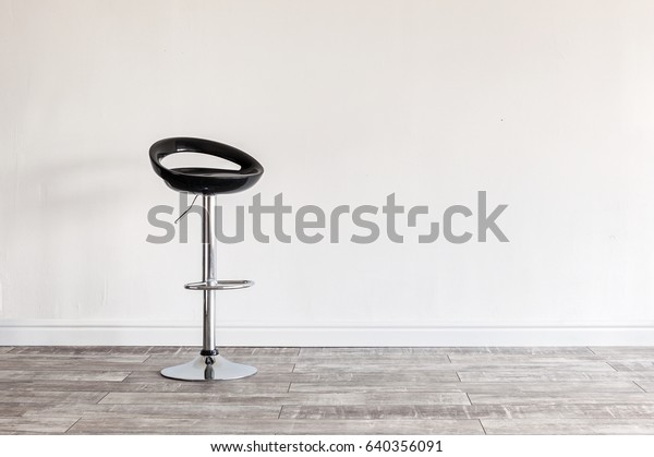 Modern\
black bar stool in front of wall with\
copyspace.