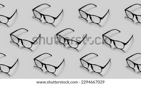 Modern black framed reading glasses or spectacles repeated on a gray colored background with minimalist style.