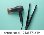 Modern black hair dryer and hair iron on blue background