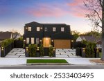 Modern black house with wooden accents and well-lit exterior at dusk in a suburban neighborhood.