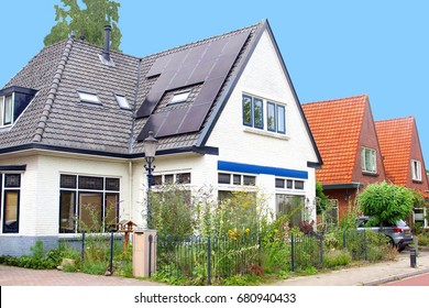 Modern black solar panels on roof of typical old Dutch house with garden flowers in suburban neighborhood street. Green electricity generation, co2 neutral  during energy crisis - Powered by Shutterstock