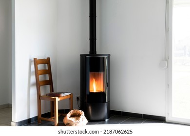 Modern black stove with burning flames and pellet bag in a living room - Shutterstock ID 2187062625