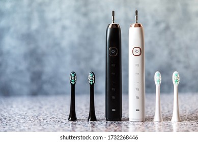 Modern black and white sonic or electric toothbrush set with replacement heads. Concept of professional oral care and healthy teeth by using sonic smart toothbrush. Minimal design