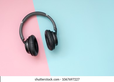 Modern black wireless headphones on a pink and blue background. The concept of music and fashion. Minimalism.