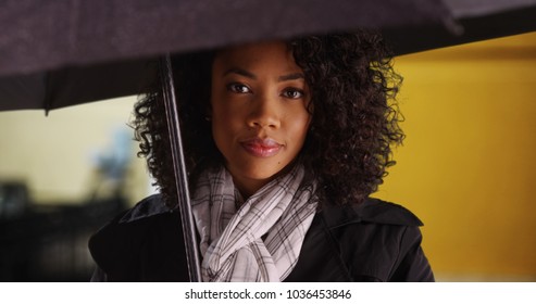 Modern Black Young Lady Holding Umbrella And Looking At Camera Casually