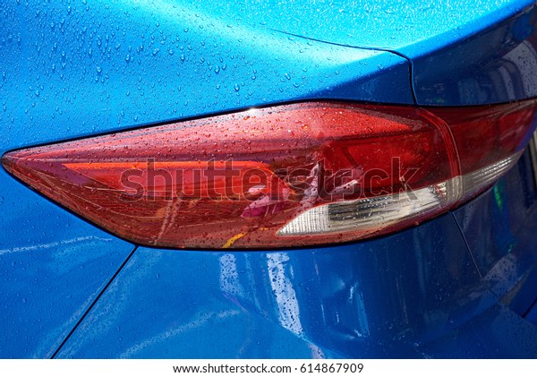 Modern blue car tail light in wet rain drop. Red\
modern car back light