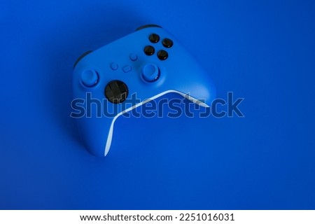 Modern blue gamepad on a blue background, game controller for video games, flat lay, copy space.