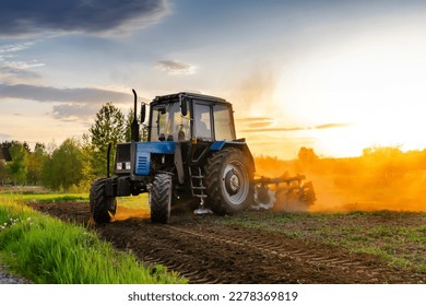 Modern blue tractor machinery plowing agricultural field meadow at farm at spring autumn during sunset. Farmer cultivating,make soil tillage before seeding plants,crops,nature countryside rural scene. - Shutterstock ID 2278369819