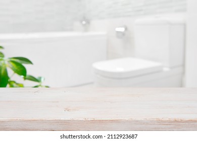 Modern blurred bathroom background with wooden table top in front - Shutterstock ID 2112923687