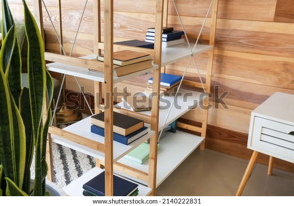 Modern book shelves\
near wooden wall in room