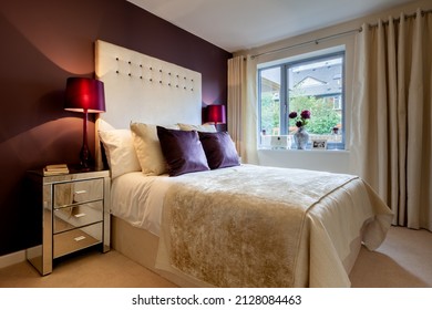 Modern Boudoir Stylised Bedroom With Gold And Burgundy Fabrics, Matching Painted Wall Ands Tall Bedside Table Lamps