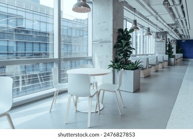 A modern break area in an office, featuring large windows that allow ample natural light to flood the space. The area is furnished with minimalist white tables and chairs. - Powered by Shutterstock