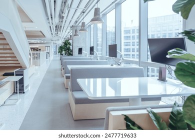 A modern break area in an office, featuring large windows that allow ample natural light to flood the space. The area is furnished with minimalist white tables and chairs. - Powered by Shutterstock