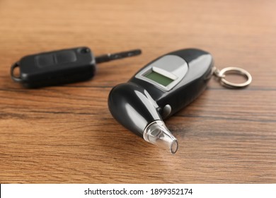 Modern Breathalyzer And Car Key On Wooden Table