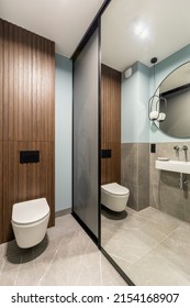 Modern Bright Bathroom With White Toilet Seat On Wooden Lamela Wall. Mirror On Grey Wall. 