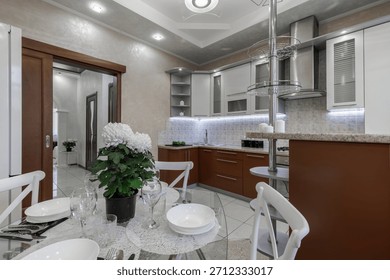 Modern bright kitchen interior with dining table, cabinetry, decor elements and a hallway view.