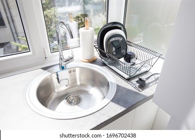 Modern Bright Kitchen Interior With Faucet And Sink, Clean Plates In Dish Drying Rack And Roll Paper Towel On Kitchen Counter. 