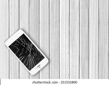 Modern broken mobile phone on white wooden background