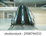 A modern building with an escalator next to a stairway. The building has multiple floors with spacious and airy areas.