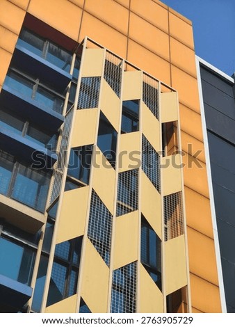 Modern building facade with geometric patterns, yellow chevron metal panels design, contemporary urban architecture style, exterior cladding of apartment complex, artistic outdoor decorative structure, design material, graphic resource, raw picture, editable image, unedited and natural look 
