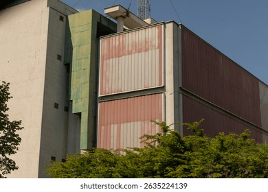 A modern building facade showcasing vibrant, colorful panels and lush greenery set against a bustling urban backdrop
