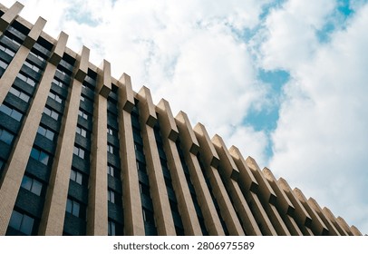 Modern building facade viewed from below against a cloudy sky