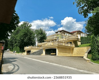 A modern building of a luxury spa hotel in the middle of a green park on a sunny summer day. A hotel in the form of a palace in a natural park. Rest in an expensive hotel