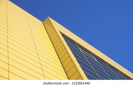 Modern building surface, diagonal and from below view in yellow and blue color with blue sky above