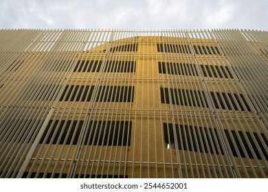 A modern building with a unique facade featuring a textured, golden exterior. This architectural design creates an eye-catching visual with its geometric patterns and interplay of light and shadow.