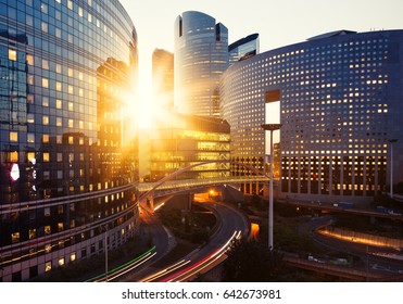 Modern buildings in Paris business district La Defense. Glass facade skyscrapers on a bright sunny day with sunbeams in the blue sky. Economics, finances, business activity and city traffic concept