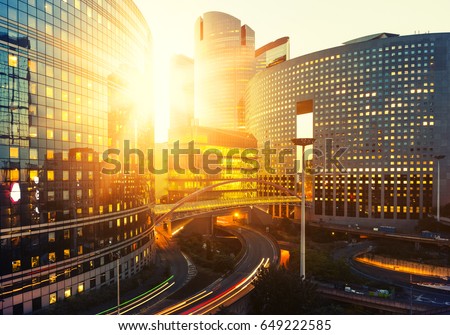 Modern buildings in Paris business district La Defense. Glass facade skyscrapers on a bright sunny day with sunbeams in the blue sky. Economy, finances, business activity and city traffic concept