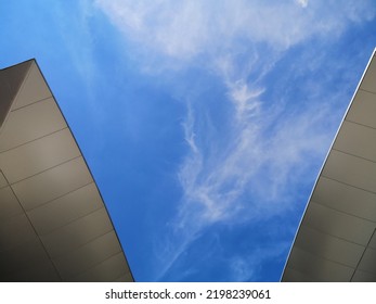 Modern Buildings, View From Below. Abstract Architecture And Material Design With Curvy Hitech Roof. Minimal Exterior Background With Curve Structure. Geometric Composition Of Curves Against Blue Sky.