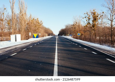 Modern Bus Shelter With Glass Design And Billboard Poster Holder Case In The Winter In Residential Urban Setting With Bare Trees, Salty Sidewalk, Wood Garbage Bin And Snowy Background. Polar Vortex.