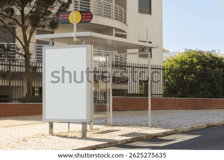 A modern bus stop with a blank advertising panel in a Portuguese urban neighborhood, bathed in daylight. The clean, structured lines contrast subtly with natural and residential elements.