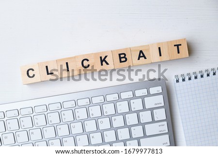 Modern business buzzword - clickbait. Top view on keyboard and notepad with wooden blocks. Close up. Top view.