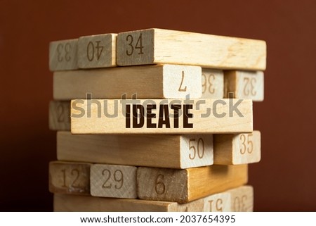 Modern business buzzword - ideate. Word on wooden blocks on a brown background. Close up.