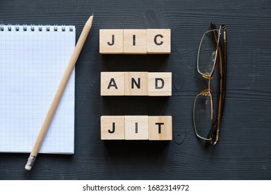 Modern business buzzword - jic and jit. Top view on glasses and notepad with wooden blocks. Close up. Top view.