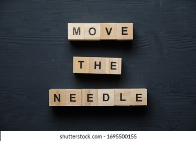 Modern business buzzword - move the needle. Top view on wooden table with blocks. Top view. Close up. - Shutterstock ID 1695500155