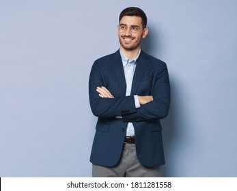 Modern Business Man Standing In Smart Casual Suit, Holding Crossed Arms, Smiling And Looking Aside, Isolated On Blue Background, Copy Space On Left