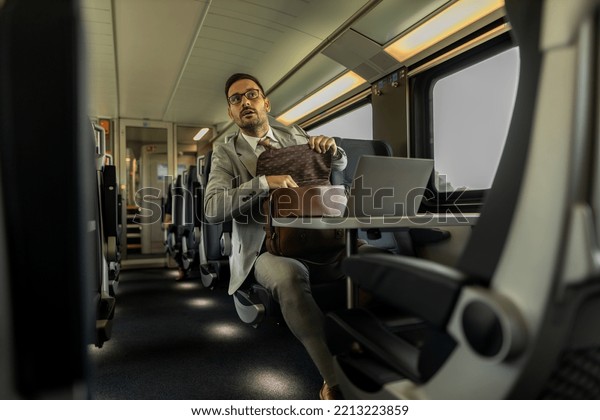 Modern\
business man in the train traveling to work. Man is using laptop,\
mobile phone, and writing down in\
notebook