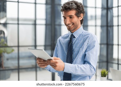 Modern business man using digital tablet while standing in the office - Shutterstock ID 2267560675